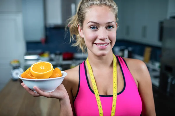 Fit woman showing bowl of oranges — Stock Photo, Image