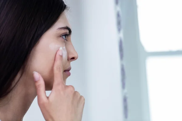 Morena aplicando crema facial — Foto de Stock