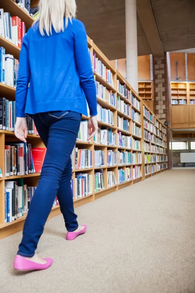 Estudante feminina caminhando na biblioteca — Fotografia de Stock