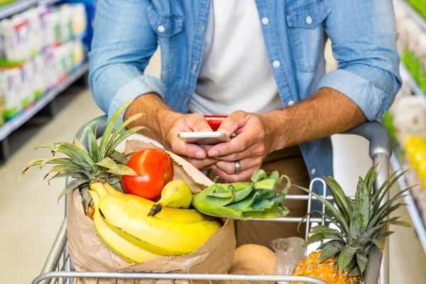 Hombre mensajes de texto y compras de comestibles —  Fotos de Stock