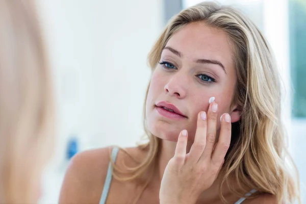 Mujer aplicando crema en la cara —  Fotos de Stock