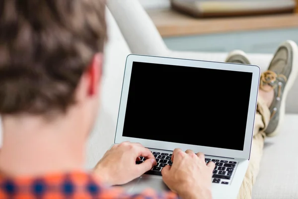 Handsome man using laptop on couch — Stock Photo, Image