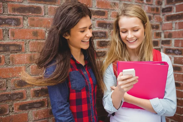 Smiling students using smartphone — Stock Photo, Image