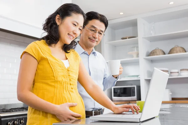 Expectant couple using laptop — 스톡 사진