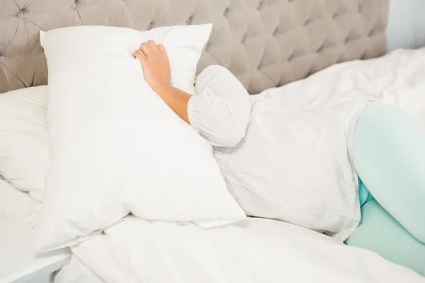 Zwangere vrouw die betrekking hebben op gezicht met kussen — Stockfoto