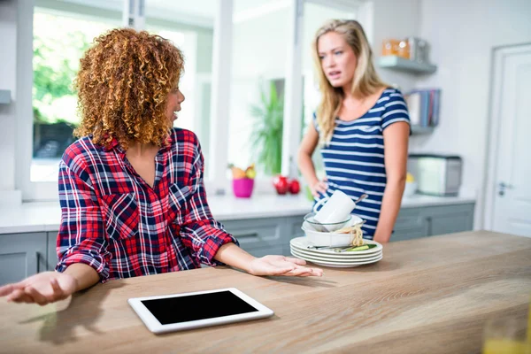Woman showing dirty dishes to friend — Stock Photo, Image
