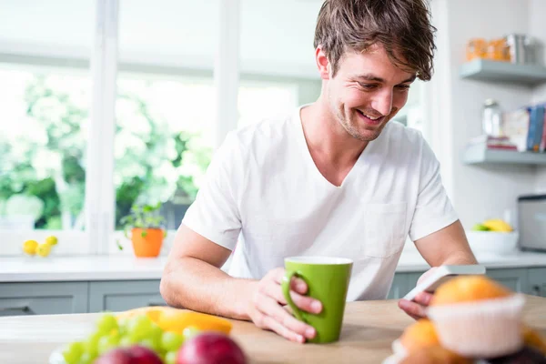 Uomo utilizzando smartphone e tazza di tenuta — Foto Stock