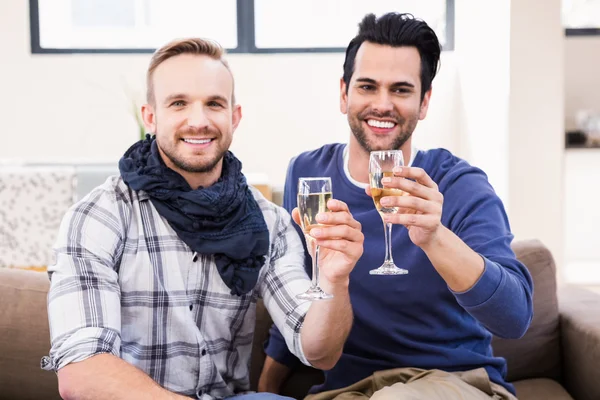 Пара геев пьет тосты на диване — стоковое фото