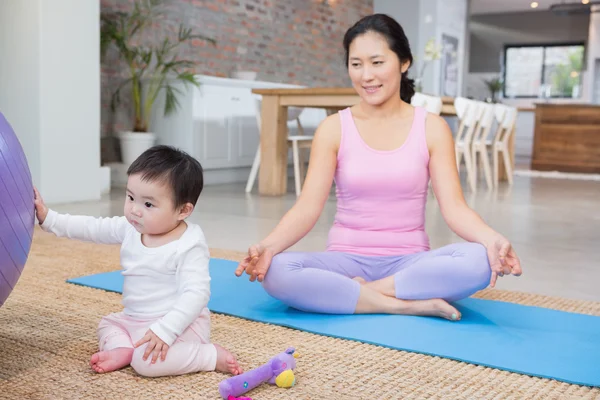 Calm mother sitting on mat at home — Stock Photo, Image
