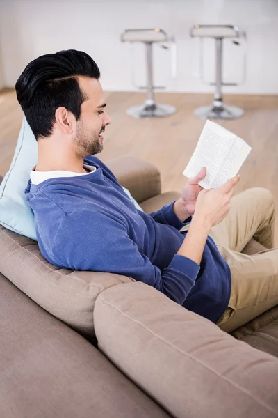 Przystojny mężczyzna czytanie książki na kanapie — Zdjęcie stockowe
