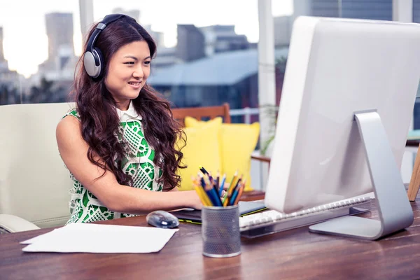 Asian woman with headphones using computer — Stock Photo, Image