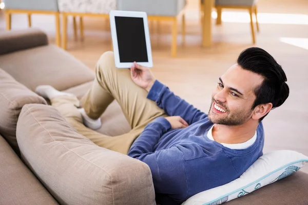 Man met behulp van Tablet PC liggend op Bank — Stockfoto