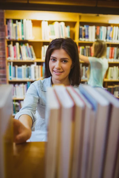 Morena escolhendo livro de estantes — Fotografia de Stock