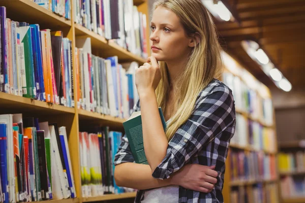 Thoughtful student looking at bookshelf Stock Photo