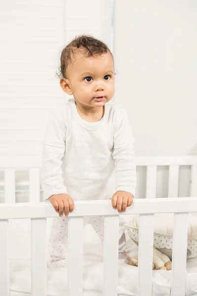 Söt baby står i spjälsängen — Stockfoto