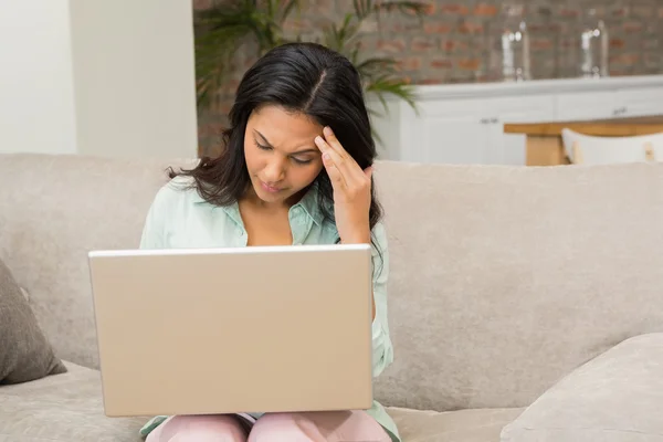 Unsmiling brunette using laptop — 图库照片