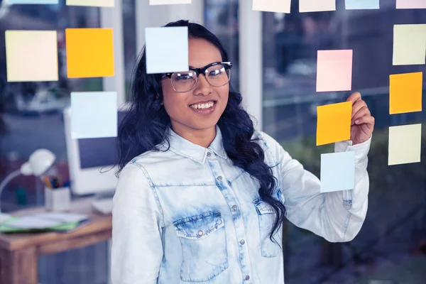 Asian woman writing on sticky notes — Stock Photo, Image