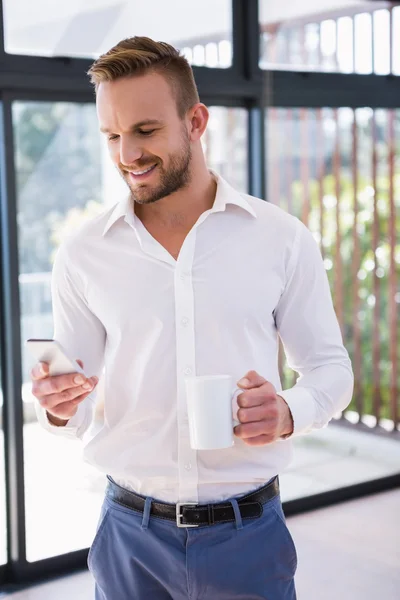 Hombre con taza y teléfono inteligente — Foto de Stock
