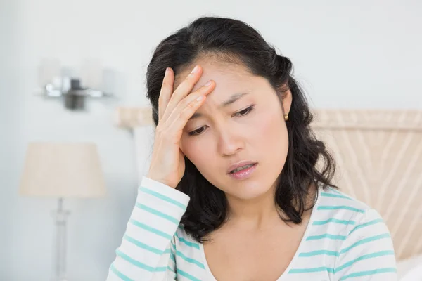 Vrouw met hoofdpijn zittend op bed — Stockfoto