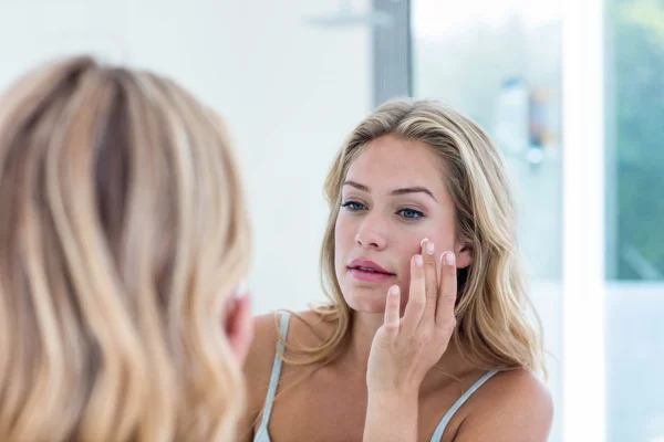 Mujer aplicando crema en la cara — Foto de Stock