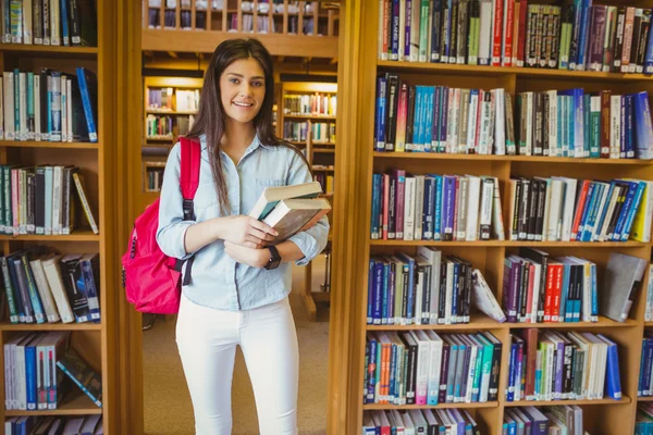 Studentin steht neben Bücherregalen — Stockfoto