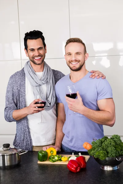 Smiling gay couple with red wine — Stock Photo, Image