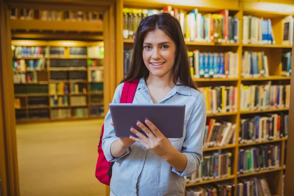 Studentin nutzt Tablet neben Bücherregal — Stockfoto