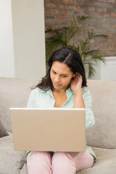 Unsmiling brunette using laptop — Stockfoto