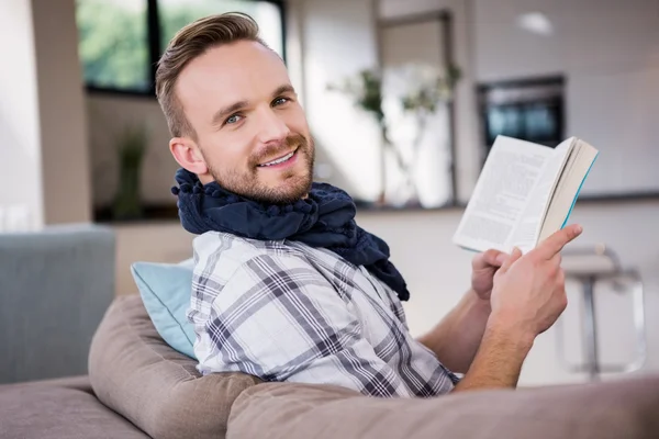 Όμορφος άντρας, διαβάζοντας το βιβλίο στον καναπέ — Φωτογραφία Αρχείου