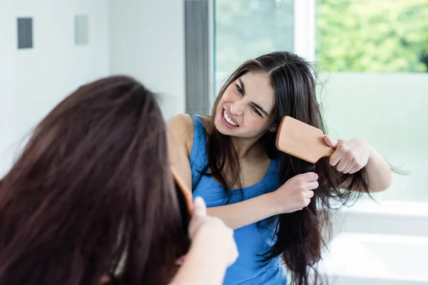 Unsmiling brunette combing — Stock Photo, Image