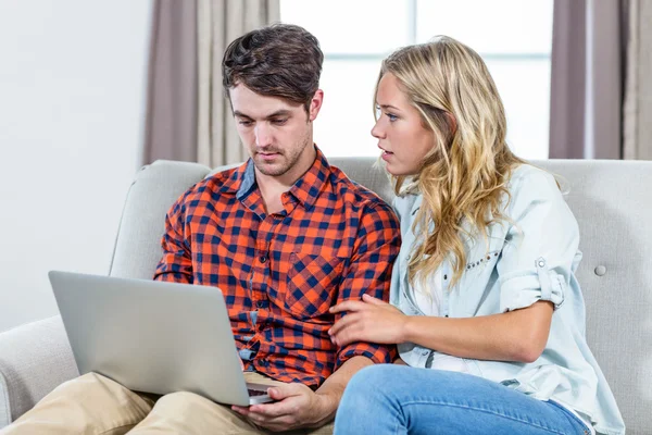 Casal usando laptop no sofá — Fotografia de Stock