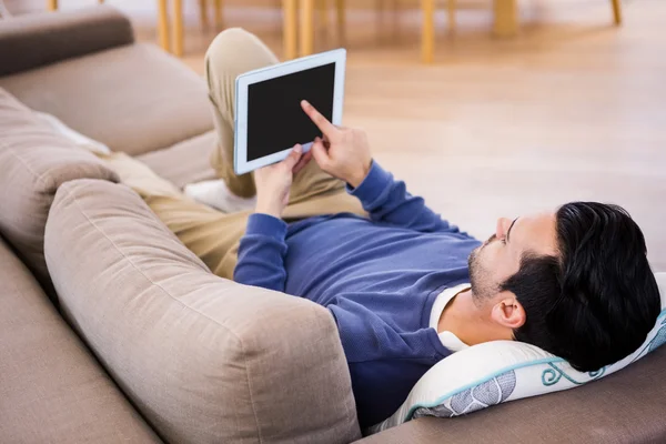 Człowiek za pomocą tabletki leżące na kanapie — Zdjęcie stockowe