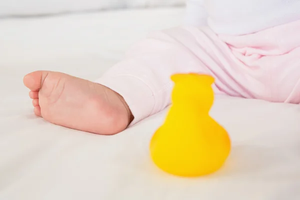 Baby foot and plastic duck — Stockfoto