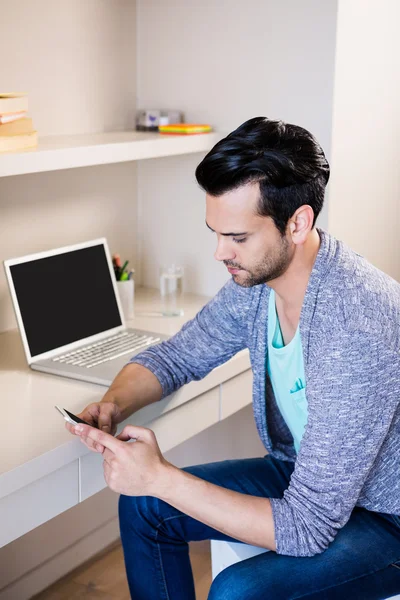Thoughtful man using smartphone and laptop — Stock Photo, Image