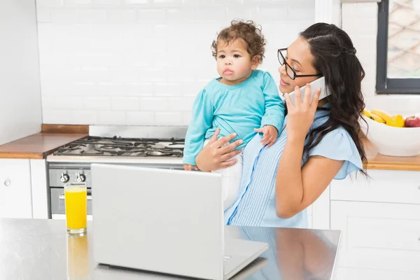 Morena sosteniendo bebé y usando portátil — Foto de Stock