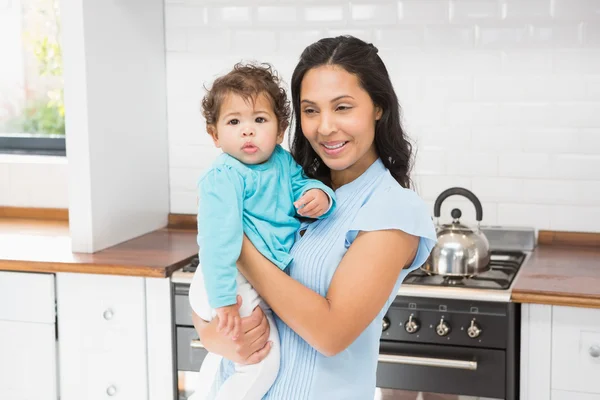 Morena sorridente segurando seu bebê — Fotografia de Stock