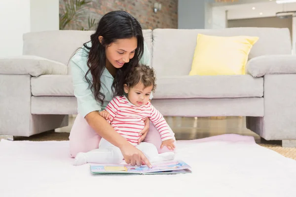 Mor med baby som ser på bok – stockfoto