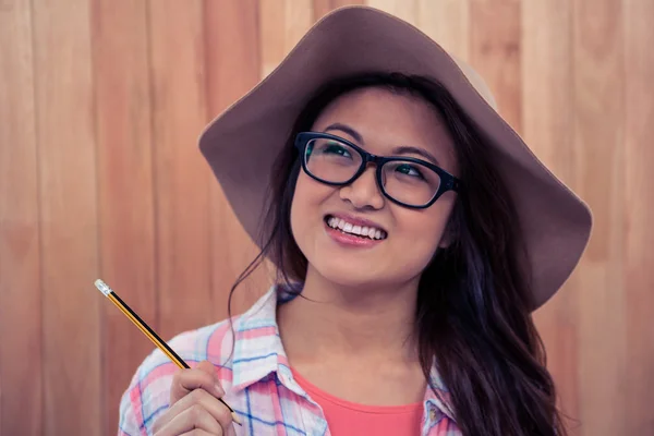 Leende asiatisk kvinna med hatt innehar penna — Stockfoto
