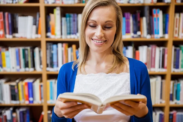 Kvinnlig student läser bok i biblioteket — Stockfoto