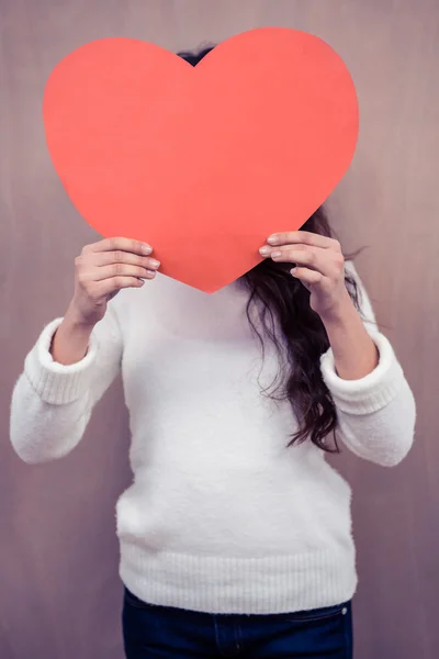 Mujer escondiendo la cara detrás del corazón de papel — Foto de Stock