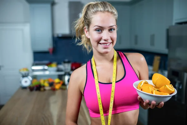 Fit vrouw toont kom van sinaasappelen — Stockfoto