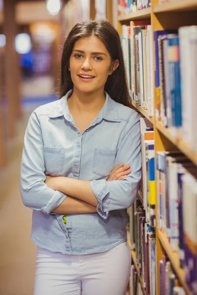 Brunette student next to bookshelves — ストック写真