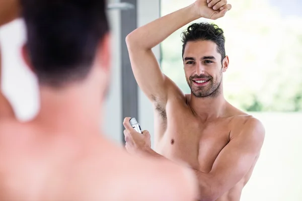 Homem sem camisa colocando desodorizante — Fotografia de Stock