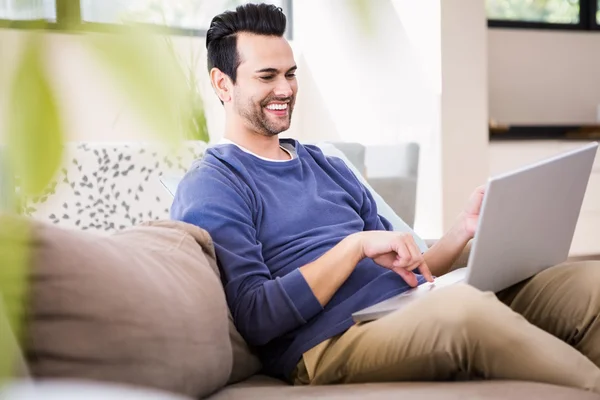 Bonito homem usando laptop no sofá — Fotografia de Stock