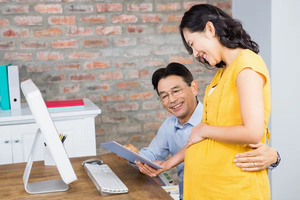 Pregnant woman showing tablet to husband — 图库照片