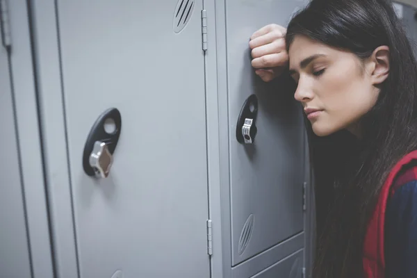 Estudante triste apoiando-se no armário — Fotografia de Stock