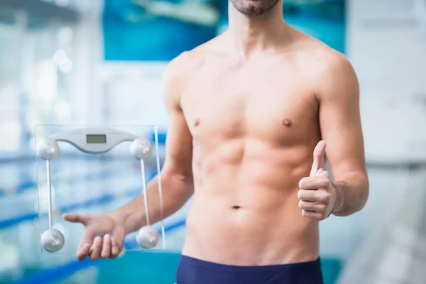 Fit homem segurando uma balança de ponderação com os polegares para cima — Fotografia de Stock