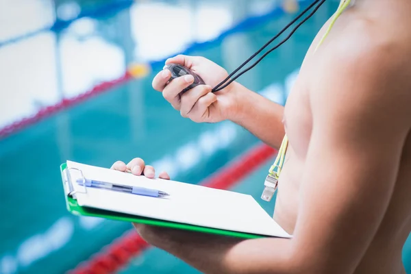 Handsome trainer holding stopwatch and clipboard — Stock Photo, Image