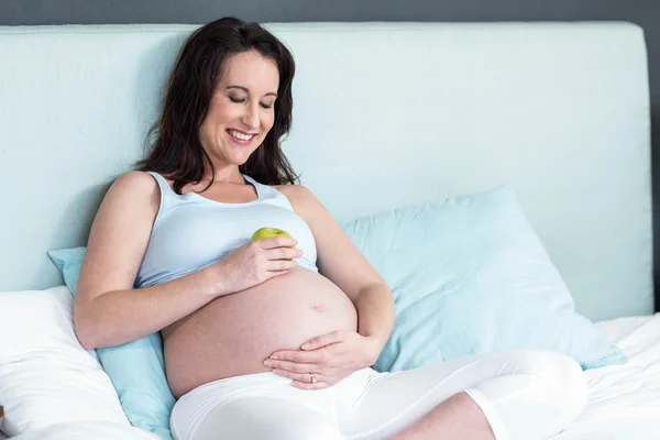 怀孕的女人一个苹果坚持她的肚子 — 图库照片