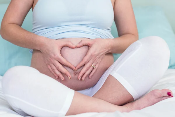 Kobieta w ciąży robi kształt serca — Zdjęcie stockowe